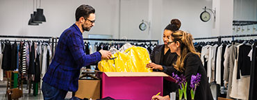 Women and man looking at clothes from a box